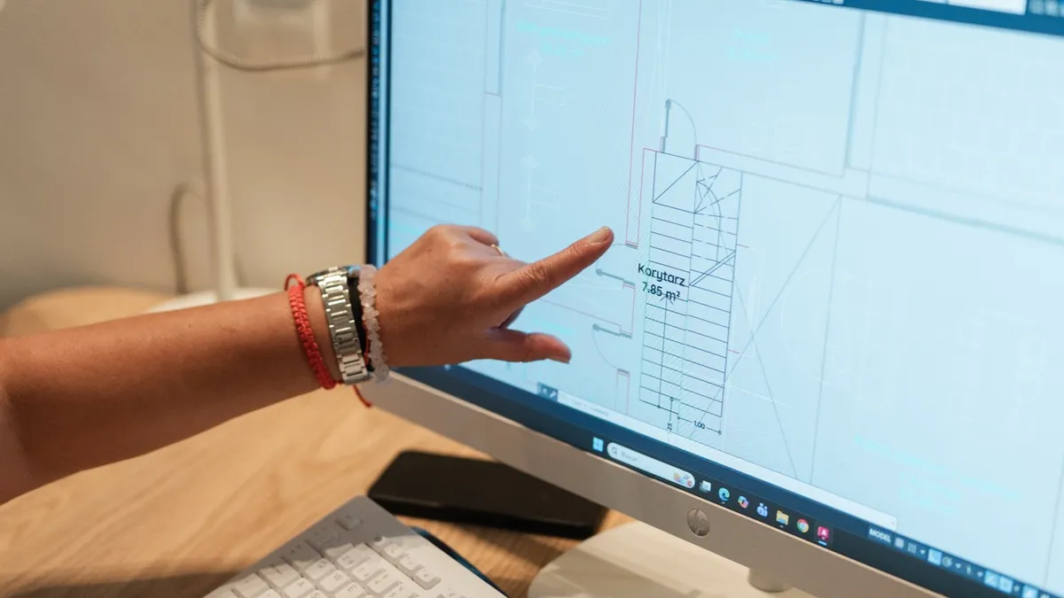 A close-up of a hand pointing to a detailed technical elevation drawing open on a computer screen.