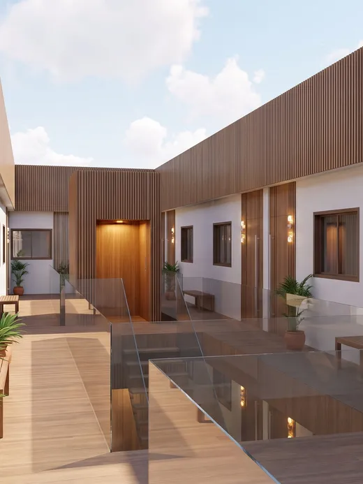 Interior courtyard walkway at Thalassa Living with timber decking, glass balustrades, potted plants, and doors to individual apartments.