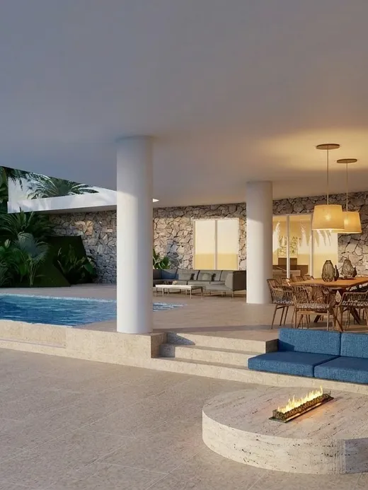 Covered outdoor lounge with a fire pit beside the pool at Draguito villa in the evening.