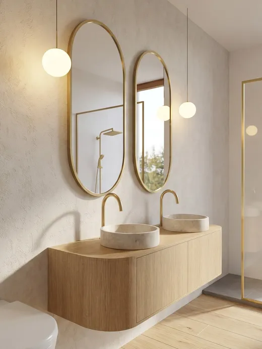 En-suite bathroom with twin stone vessel sinks, oval brass-framed mirrors, and a walk-in glass shower opening onto a garden view.