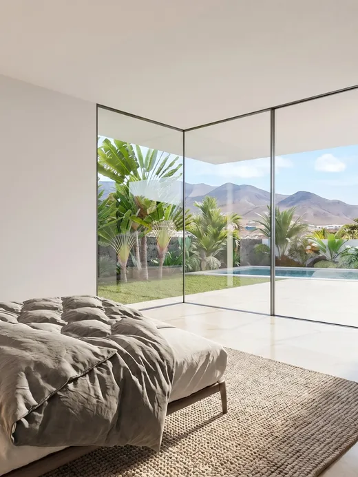 Bedroom with a floor-to-ceiling glazed corner opening onto the pool terrace and mountain views, with a walnut wardrobe to one side.