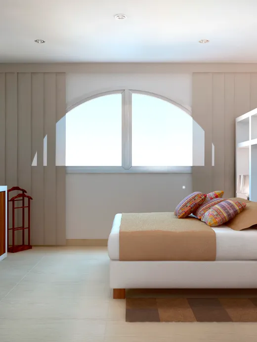 Bedroom with an arched window, a warm wood dresser and layered beige bedding.