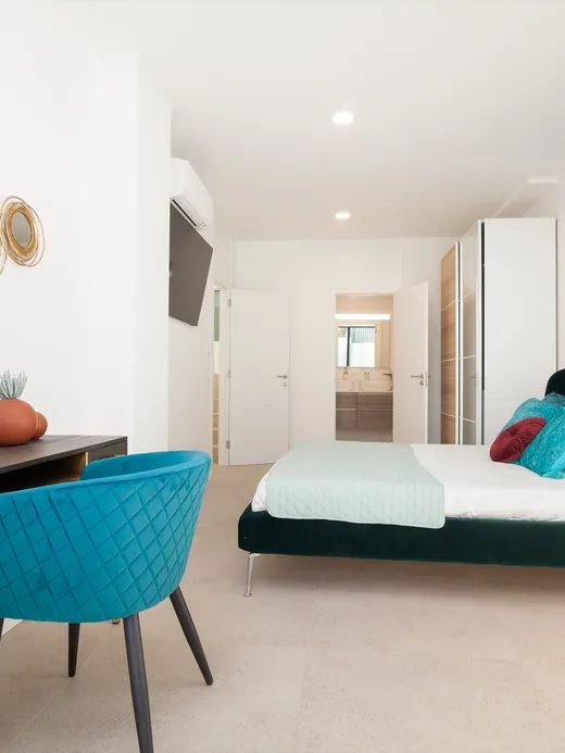Bedroom with a blue-and-copper fluid-art headboard wall, a teal velvet desk chair and gold mirror detailing.