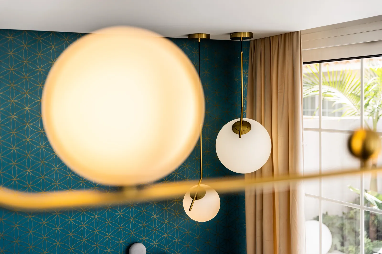 Deep-blue geometric wallpaper with a pair of warm brass globe pendant lights.