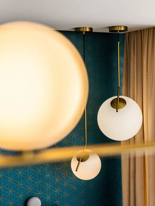 Deep-blue geometric wallpaper with a pair of warm brass globe pendant lights.