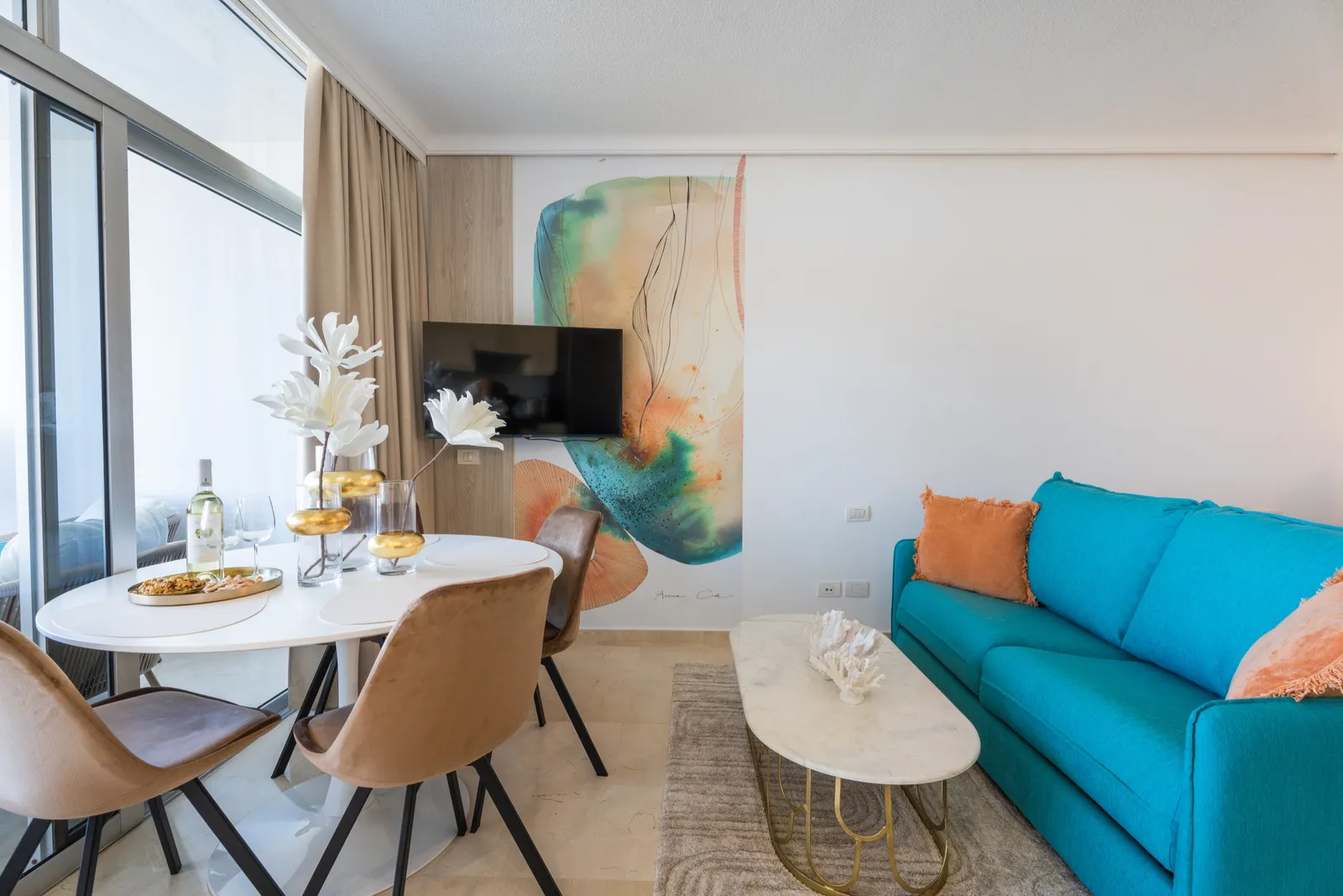 Console styled with white ceramics beneath a large coral-and-blue mural and an organic-shaped mirror.