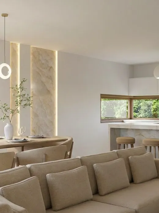 Open dining and kitchen area with a ring-pendant light fixture, a wood dining table, and a marble-topped kitchen island with bar stools.