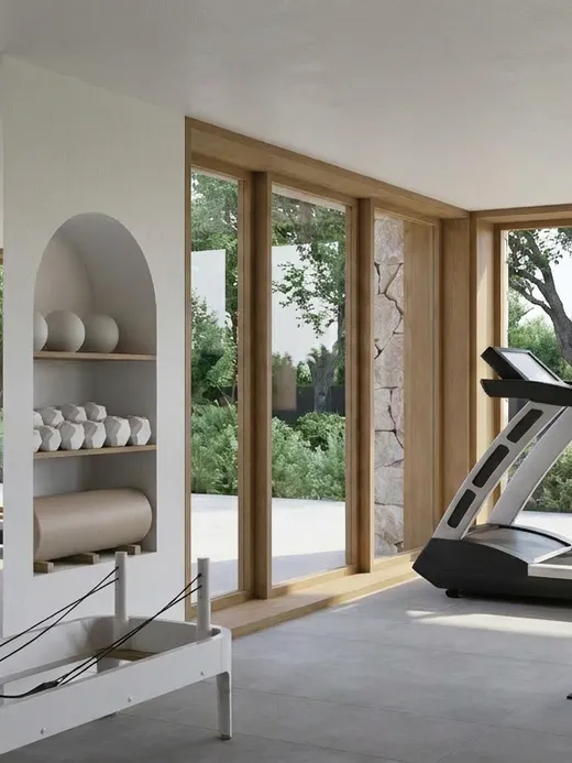 Home gym with a weight bench, treadmill, mirrored wall, and full-height windows opening onto the garden terrace.