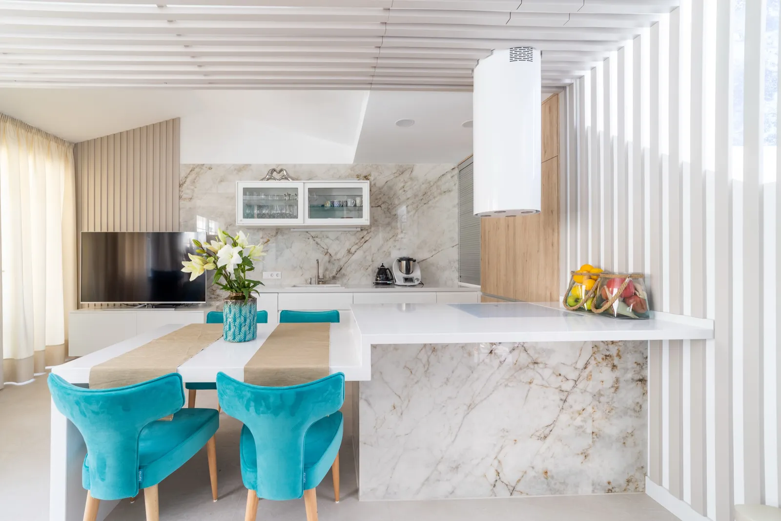 Marble kitchen island with turquoise velvet chairs, a slatted timber ceiling and a vertical timber screen dividing the space.