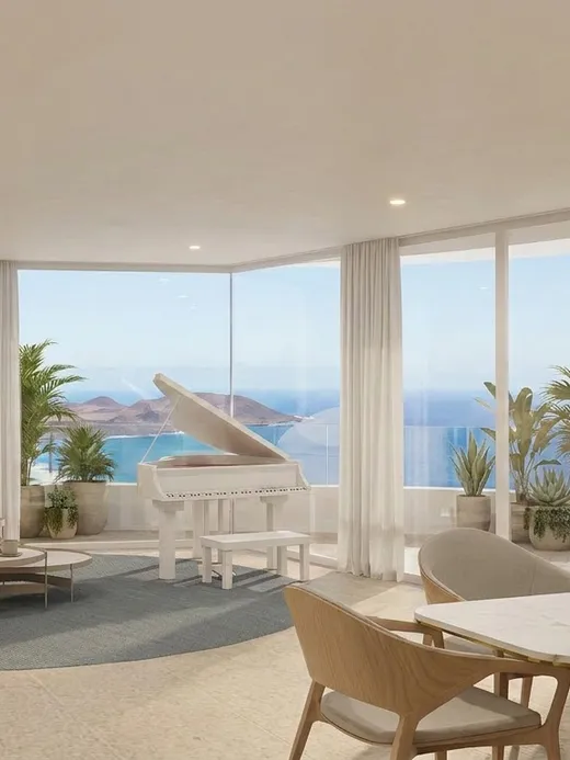 Open living and dining room at Draguito villa with a grand piano and floor-to-ceiling glazing facing the sea.