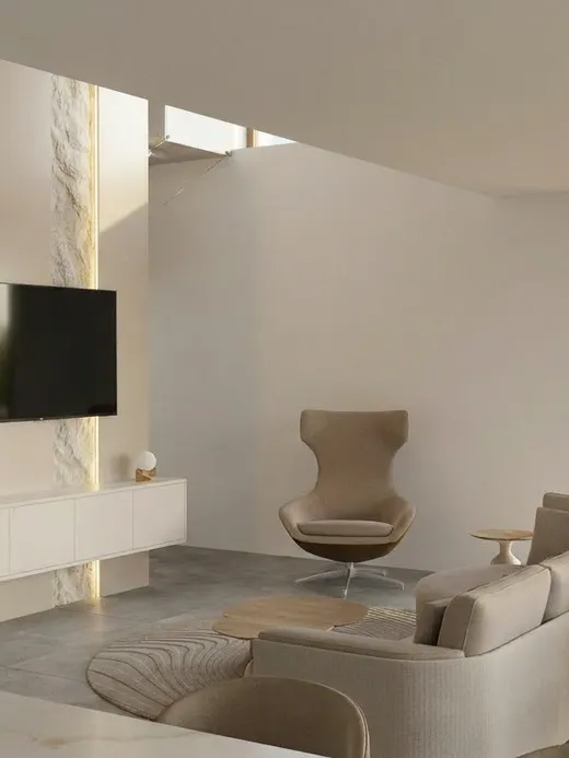 Double-height living room with a stone feature wall, a wall-mounted television, a curved swivel armchair, and a beige sectional sofa, open to the dining area beyond.
