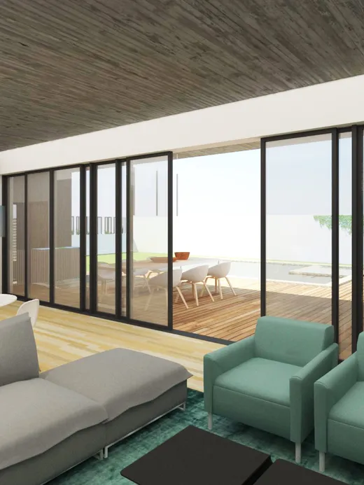 Open living and kitchen space with a concrete ceiling, teal armchairs and floor-to-ceiling glazing onto the terrace and pool.