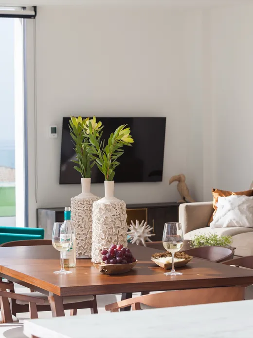 Living and dining area with turquoise chairs and a fluid-art wall in blues and coppers, framed by floor-to-ceiling windows onto the terrace.