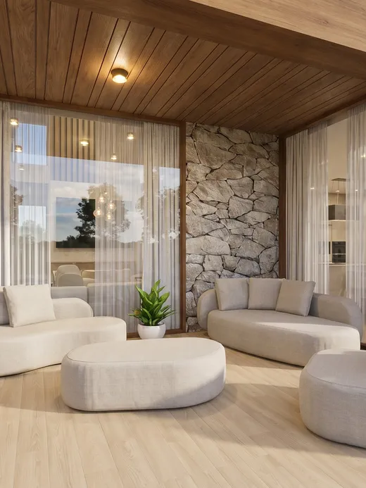 Double-height family lounge under a wood-clad ceiling, with curved upholstered sofas, a stone accent wall, and glazed views into the garden.